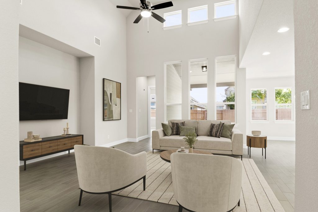 Image of staged living room with beige modern sofas and chairs with a rug and coffee tables along with a TV and TV stand
