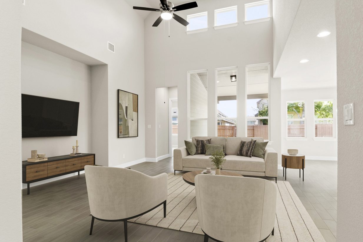 Image of staged living room with beige modern sofas and chairs with a rug and coffee tables along with a TV and TV stand