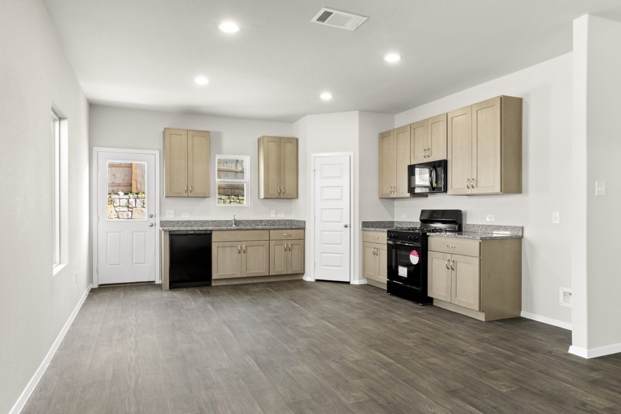 Image of a one story home dining room with light brown cabinets and black appliances with a window above the sink