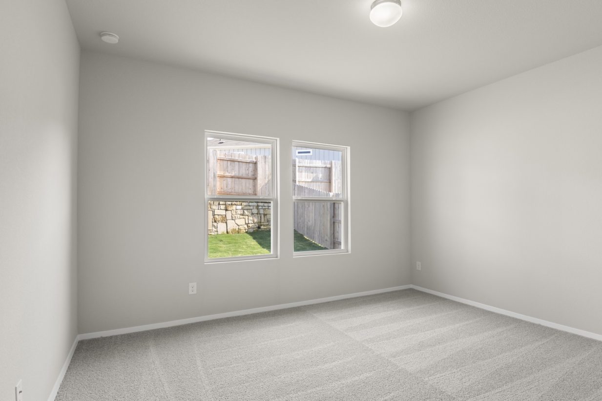 Image of primary bedroom with light grey carpet and light grey walls with two windows