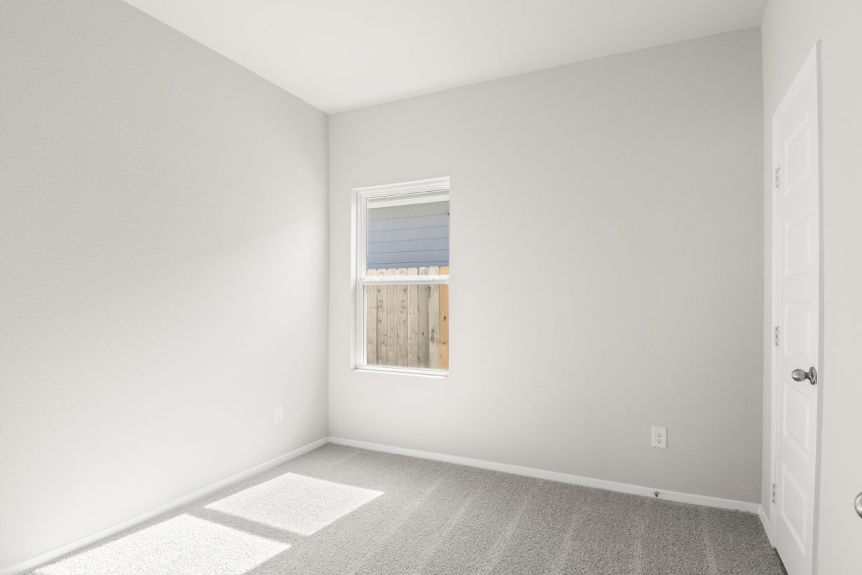 Image of a bedroom with light grey carpet and painted walls with a window