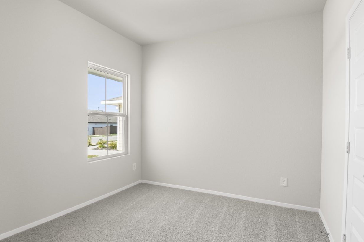 Image of bedroom with light grey carpet and walls with a window