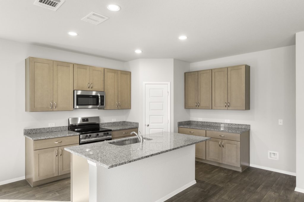 Image of a L shaped kitchen with a center island, granite counter tops, black appliances, and light brown cabinets