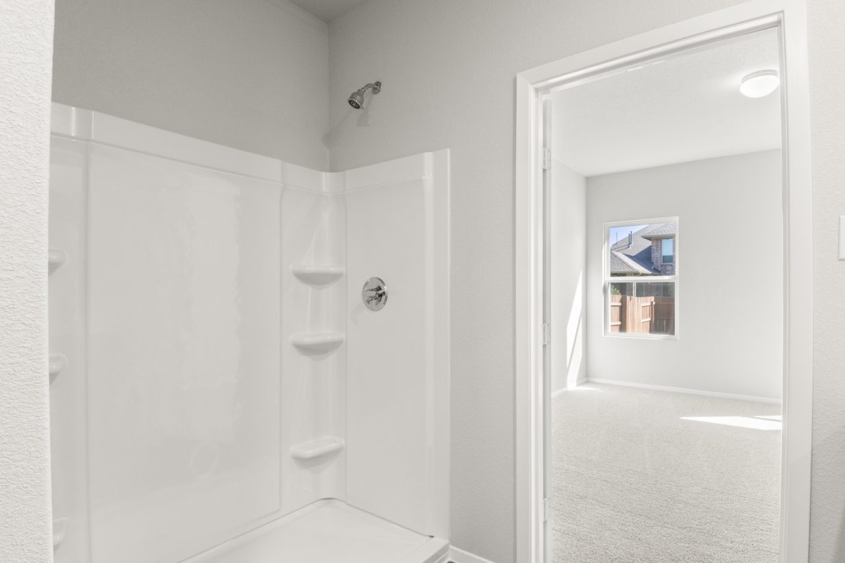 Image of a bathroom with a white vinyl standing shower and a connected primary bedroom