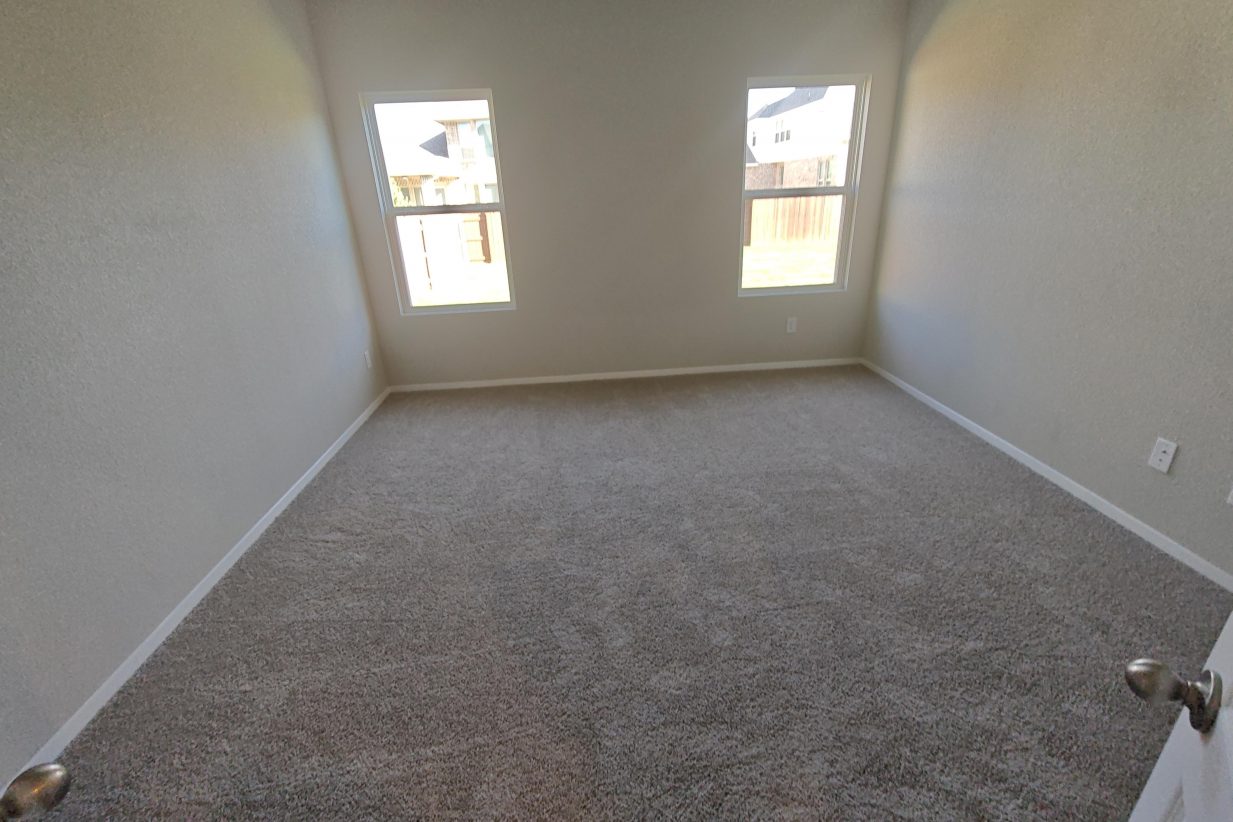 Image of bedroom with brown carpet, white painted walls, and two white framed windows.