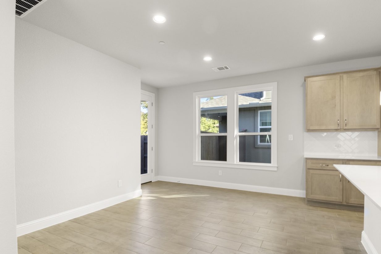 Image of a dining room with a open kitchen and a glass back door leading to the backyard