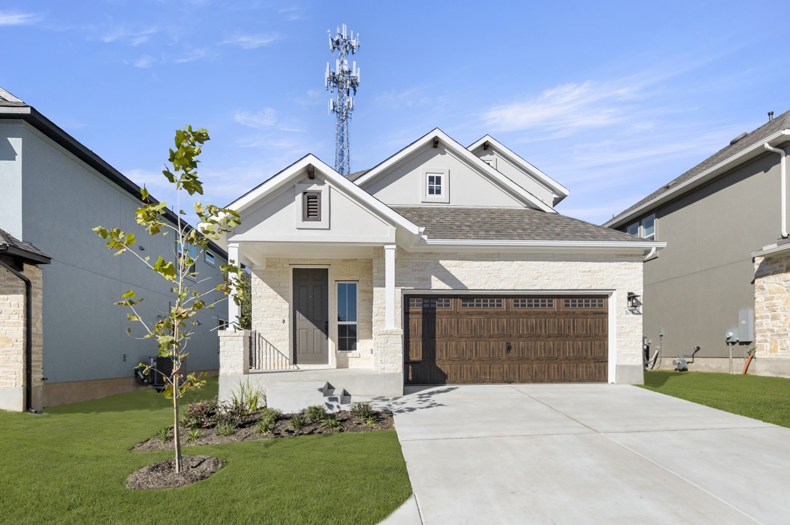 Front exterior of two-story house with a brown garage door with a driveway and green landscape.