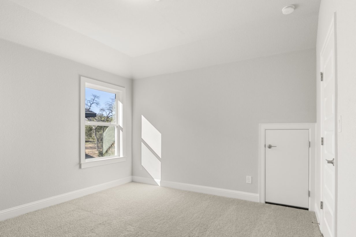 Image of a bedroom with tan carpeting and light grey painted walls with a window and white half door