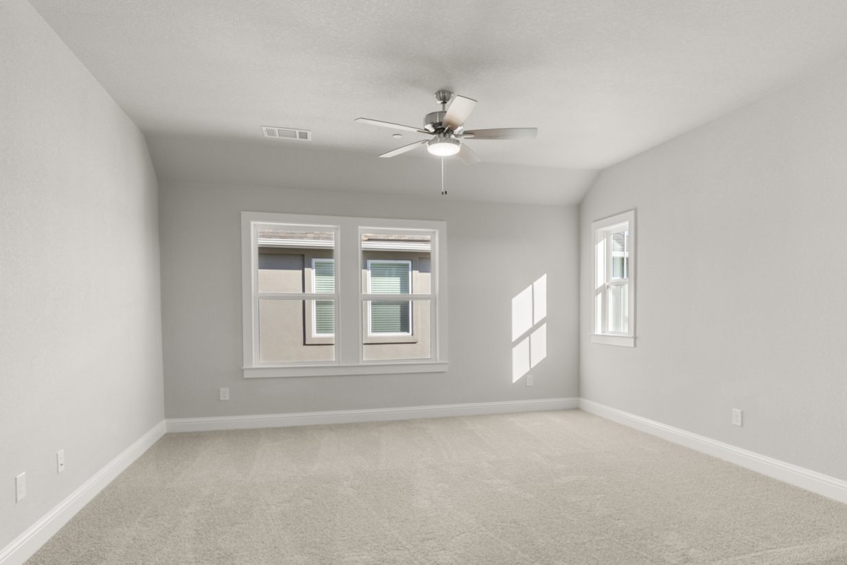 Image of a flex room with tan carpeting and light grey painted walls with two windows and a ceiling fan
