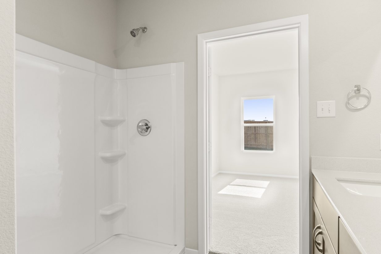Image of a primary bathroom with a white walk-in shower and a doorway to the primary bedroom