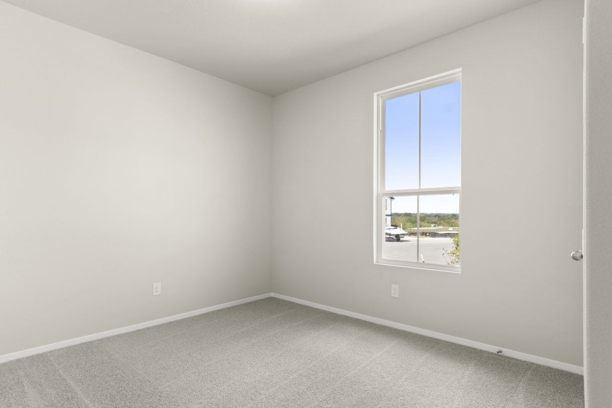 Image of tan carpeting, light grey walls and a window
