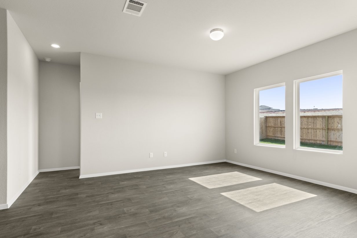 Image of a living room with dark vinyl flooring, cream walls and a window with white trim