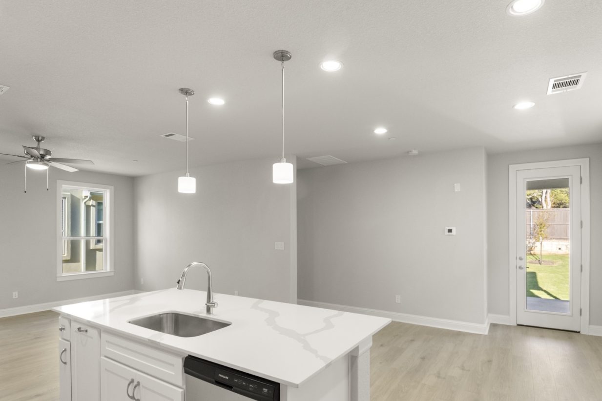 Image of a kitchen with a white island with a stainless steel sink overlooking the dining area