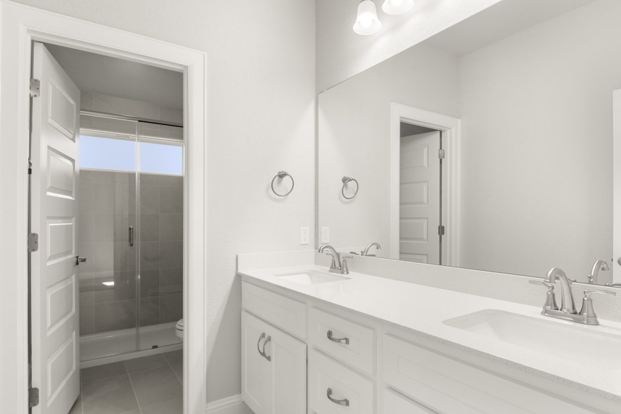Image of a bathroom with a private water closet and white cabinets with a jack and jill vanity and a large mirror
