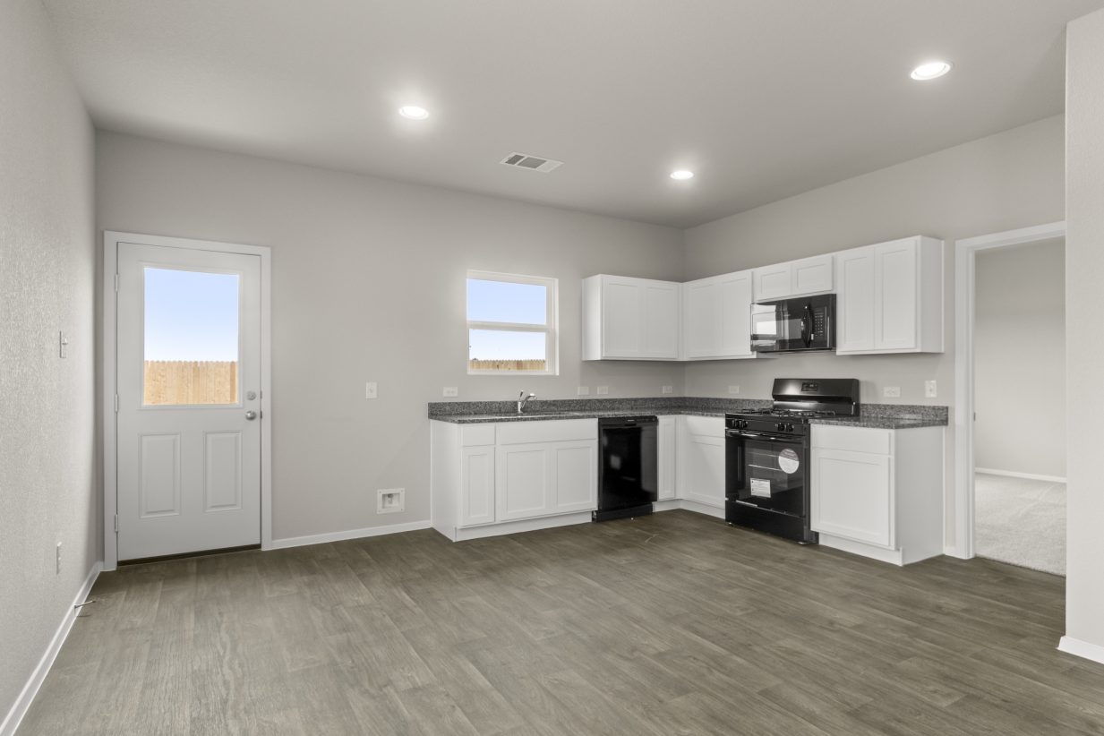Image of kitchen with white cabinets, window over sink, rear door with window and wood-look floor