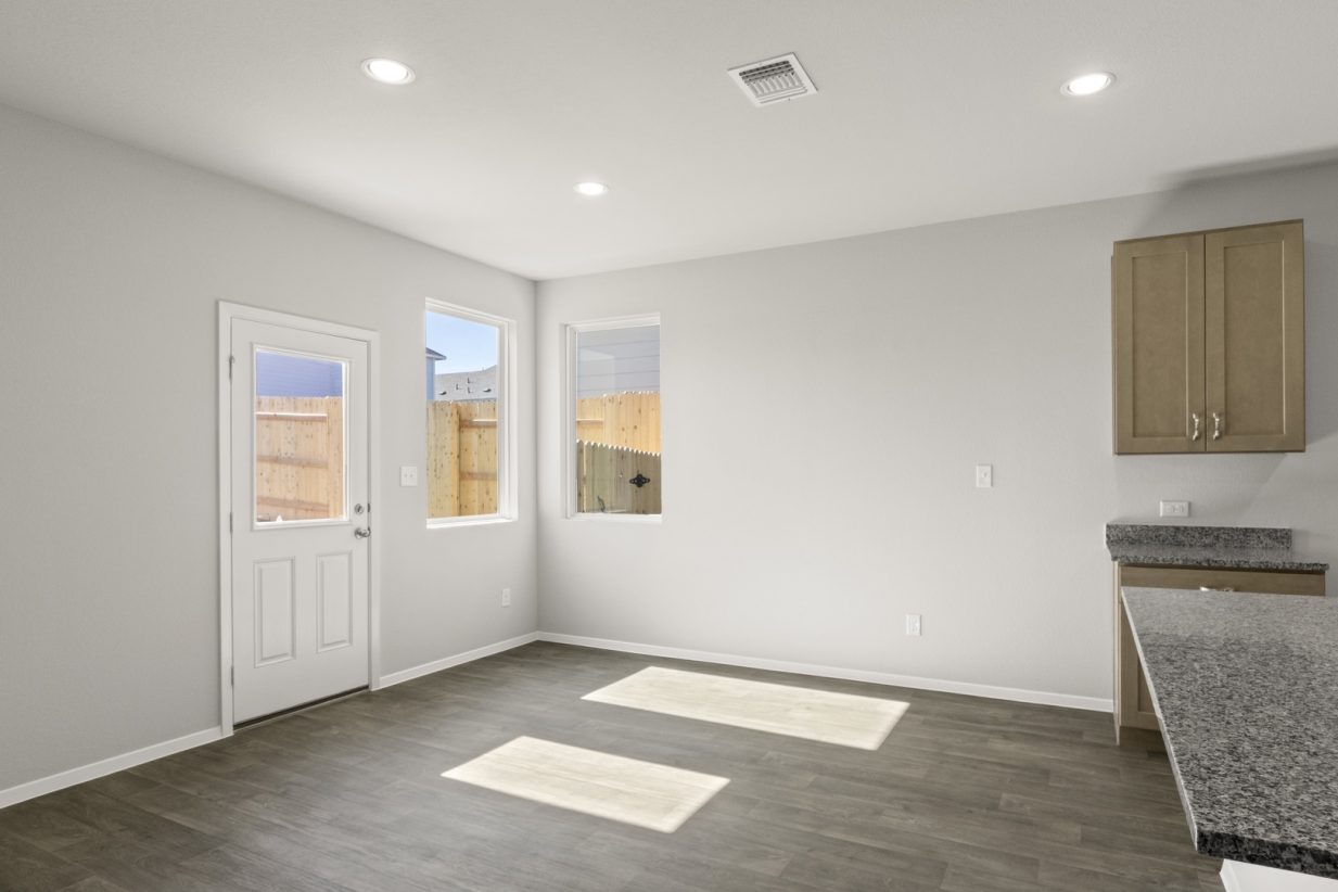 image of a dining room with dark wood-like flooring and light grey painted walls with a white back door