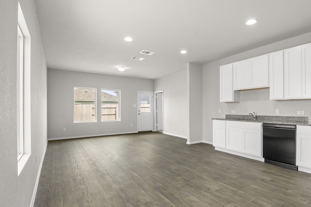 An image of wood vinyl flooring, a cream colored pained walls, white cabinets with grey countertops, and white framed windows.
