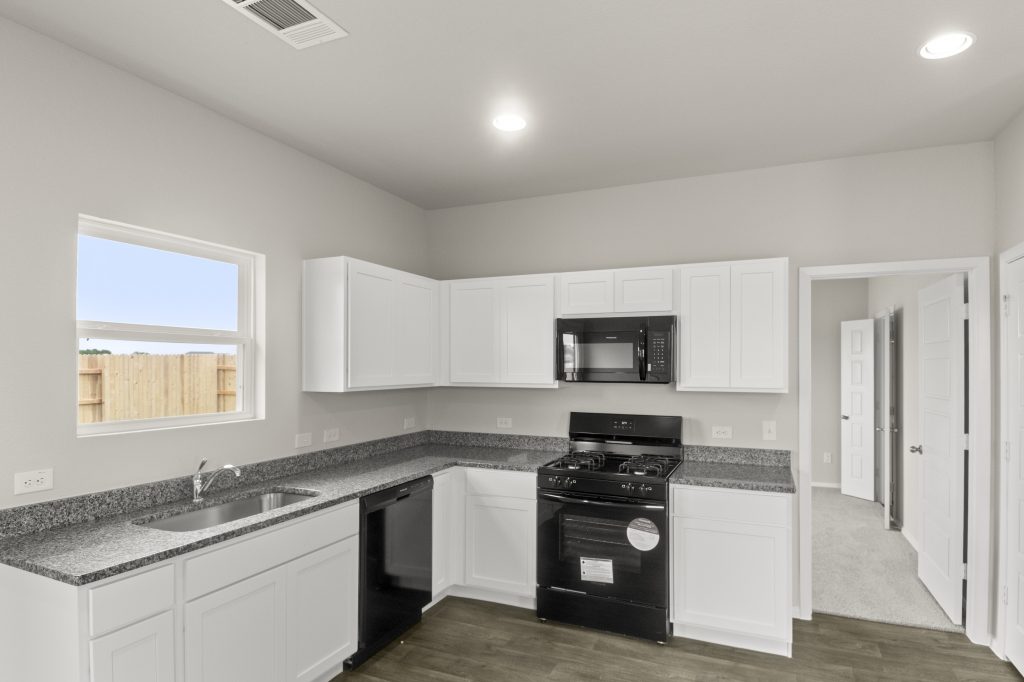Image of kitchen with white cabinets, window over sink, and wood-look floor