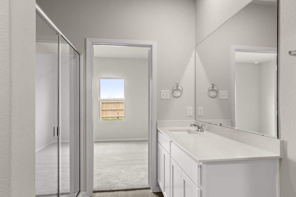 Image of en-suite bathroom with white vanity and cabinets on right and walk-in shower on left