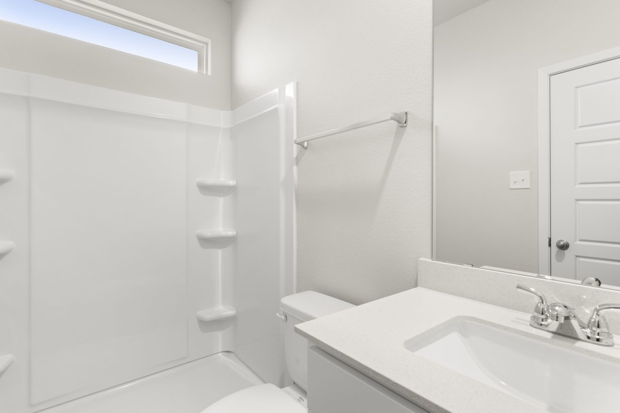 Image of a primary bathroom with a white vanity, a white shower ILO tub and a window above