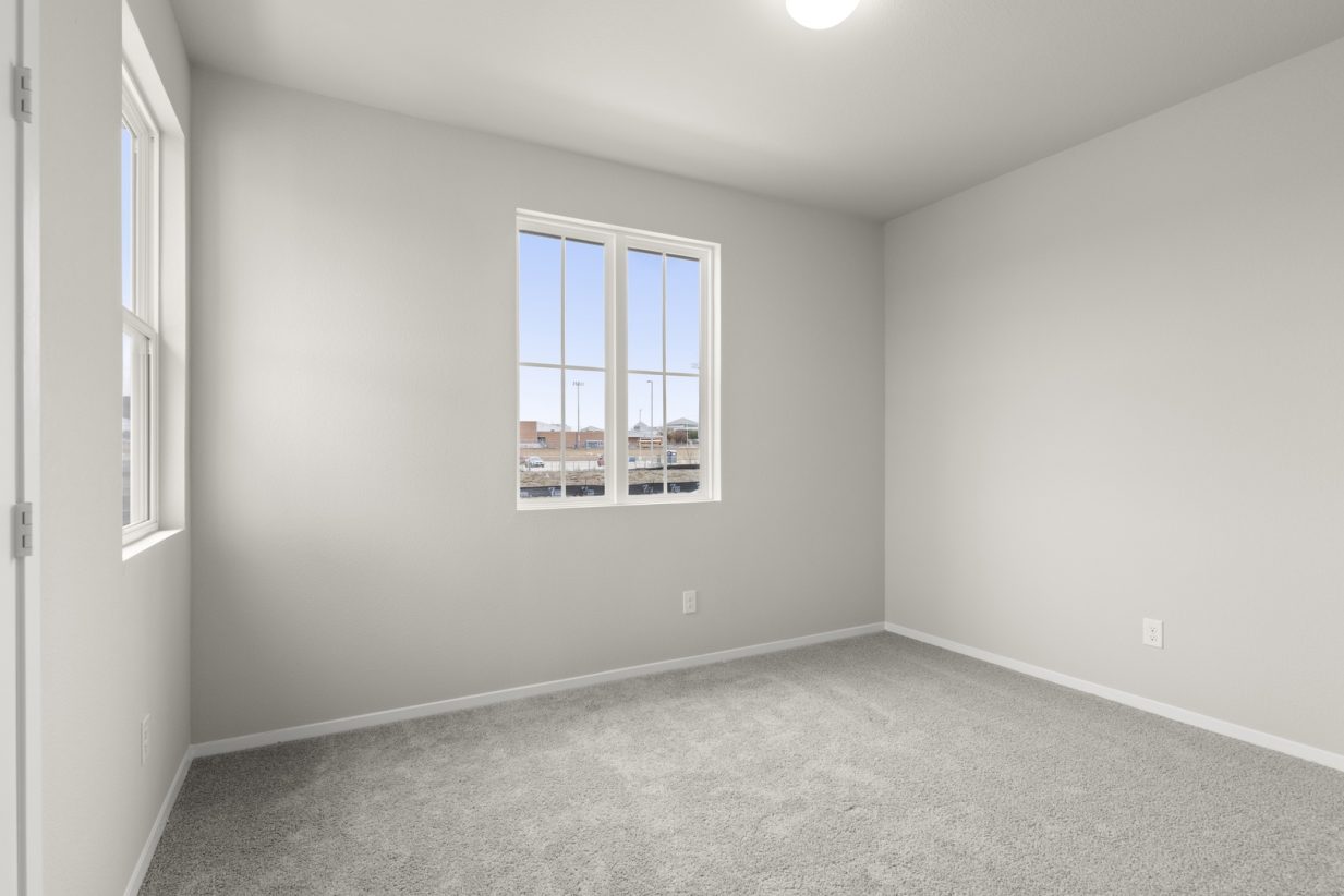 Image of a bedroom with cream walls, light grey carpeting, windows and a white trim