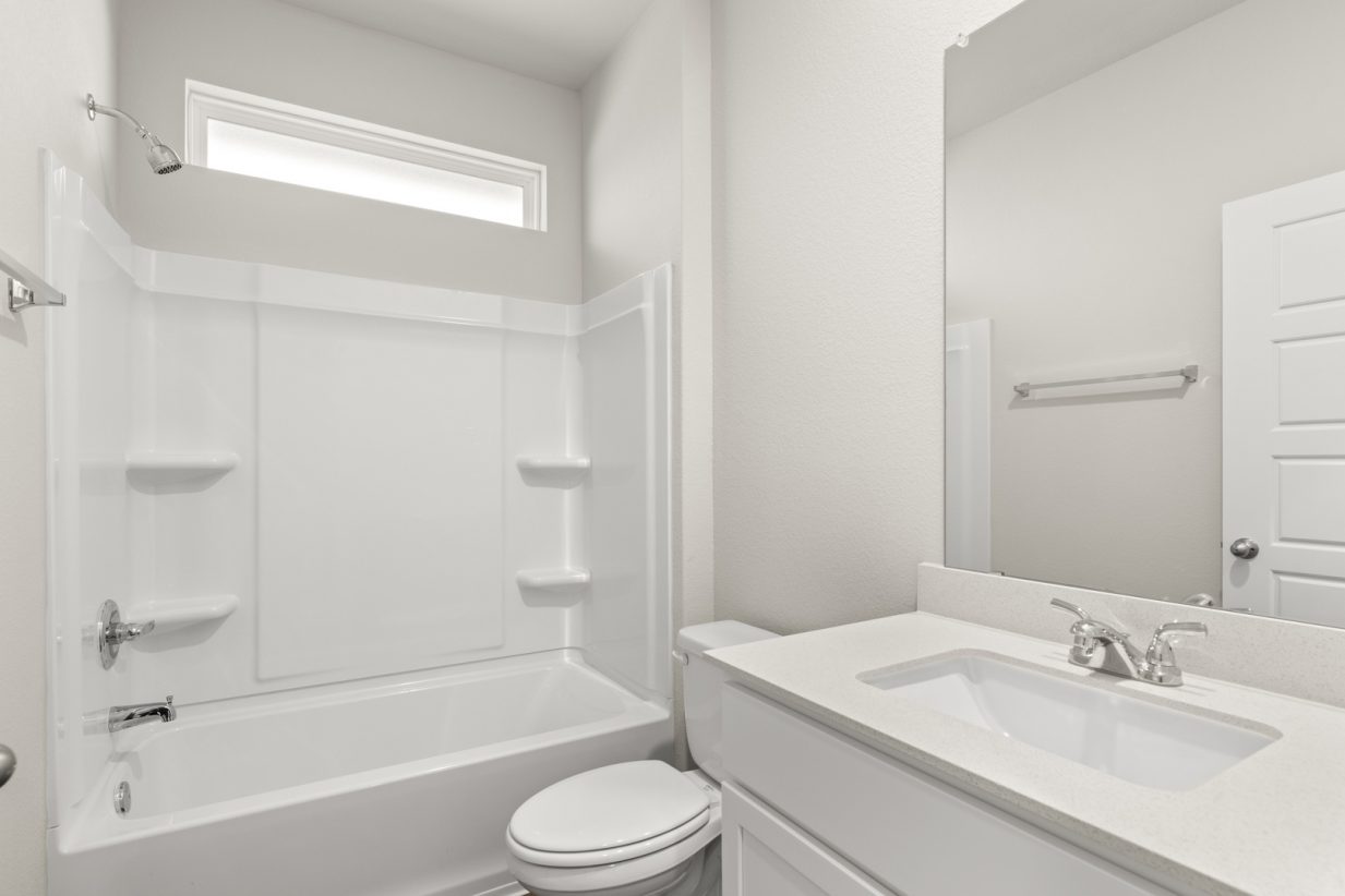Image of a bathroom with a white vanity, a white shower ILO tub with a window above and a mirror