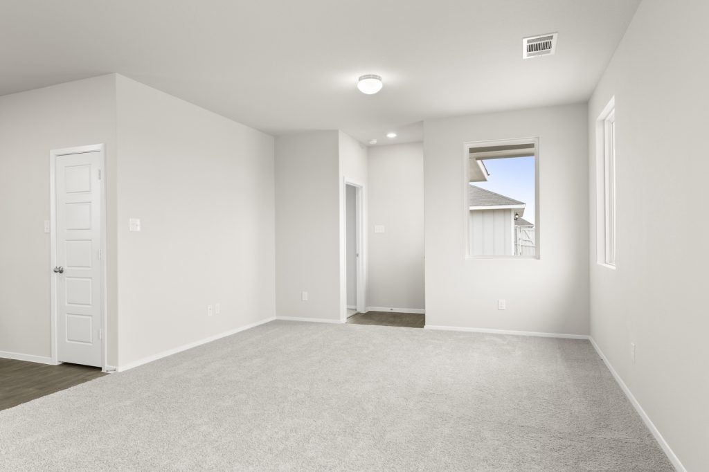 Image of a living room with cream walls, light gray carpeting, windows and white trim