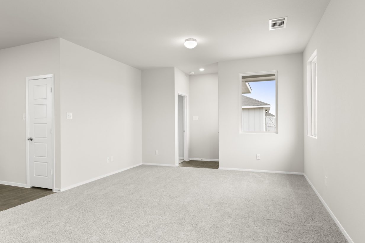 Image of a living room with cream walls, light gray carpeting, windows and white trim