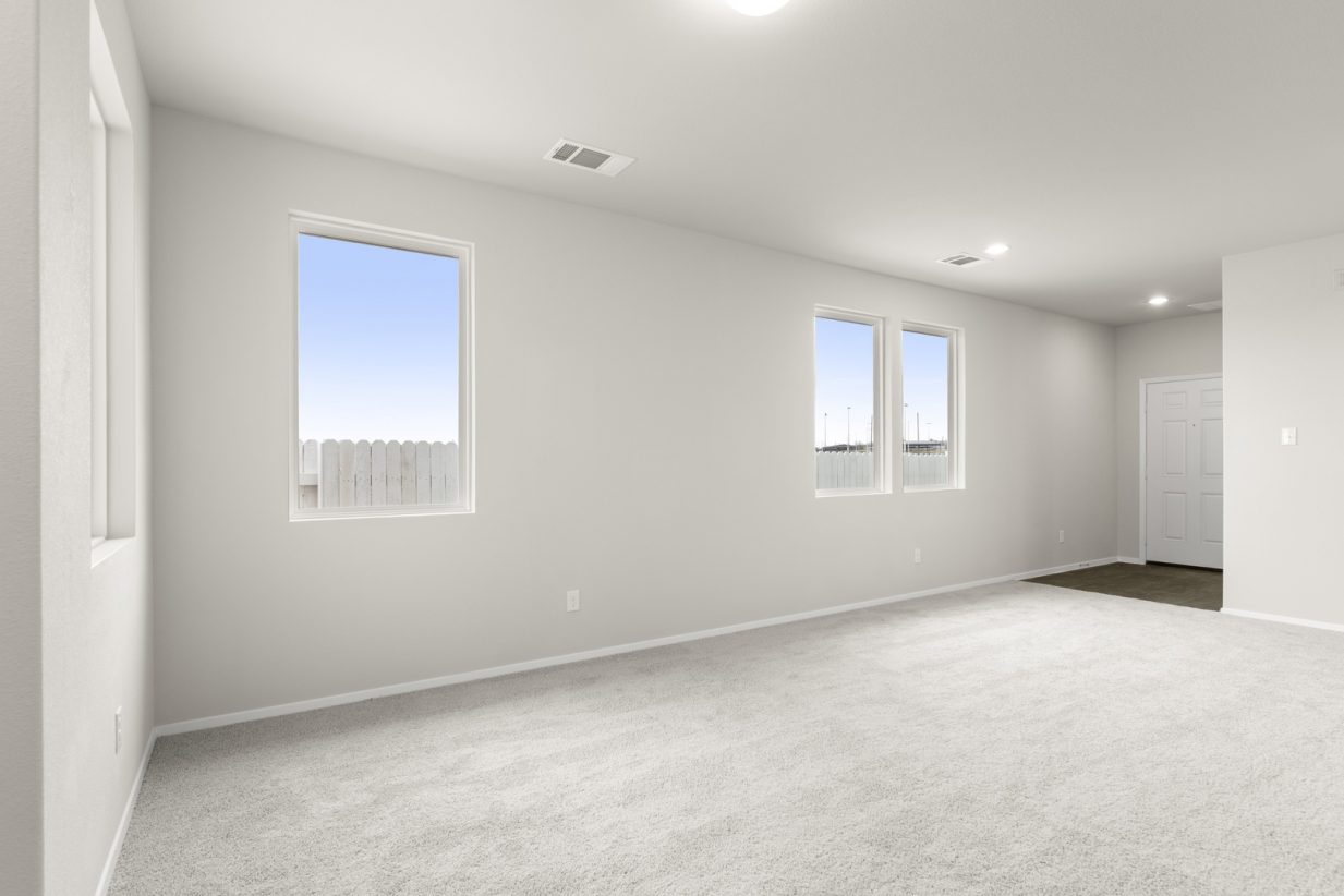 Image of a living room with cream walls, light grey carpeting, windows and white trim