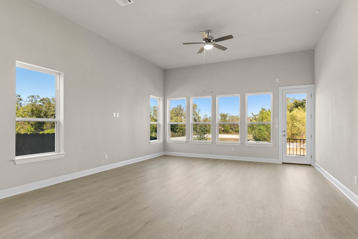 Image of dining/ living room area with light wood-like flooring and a ceiling fan and windows