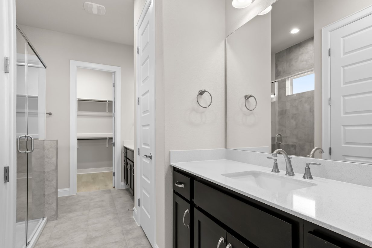 Image of primary bathroom with a walk in shower and white vanity and mirror