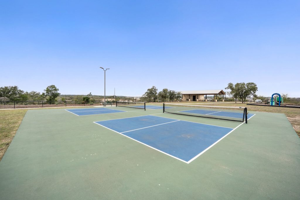 Image of a blue and green tennis court with a blue clear sky