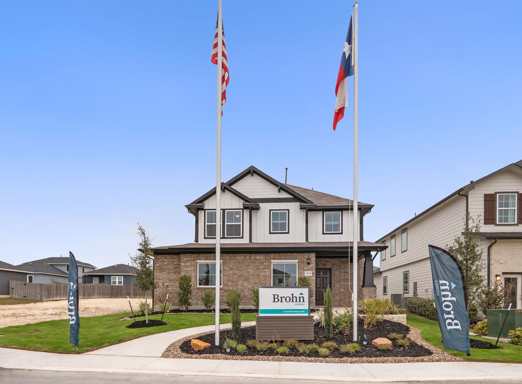 Image of Hunters Ranch front exterior model home with two flag poles and a Brohn Homes sign