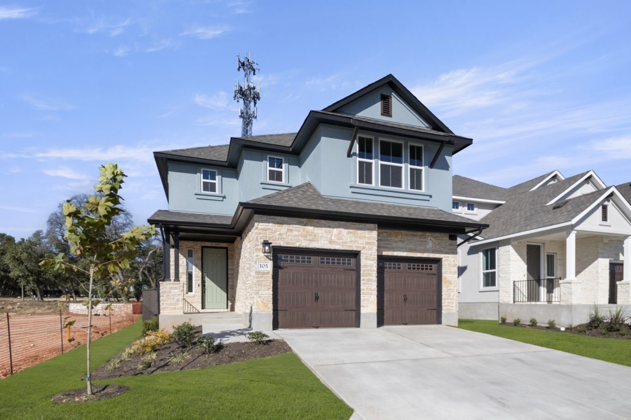 Front exterior of a blue two-story house with a double brown garage and driveway.