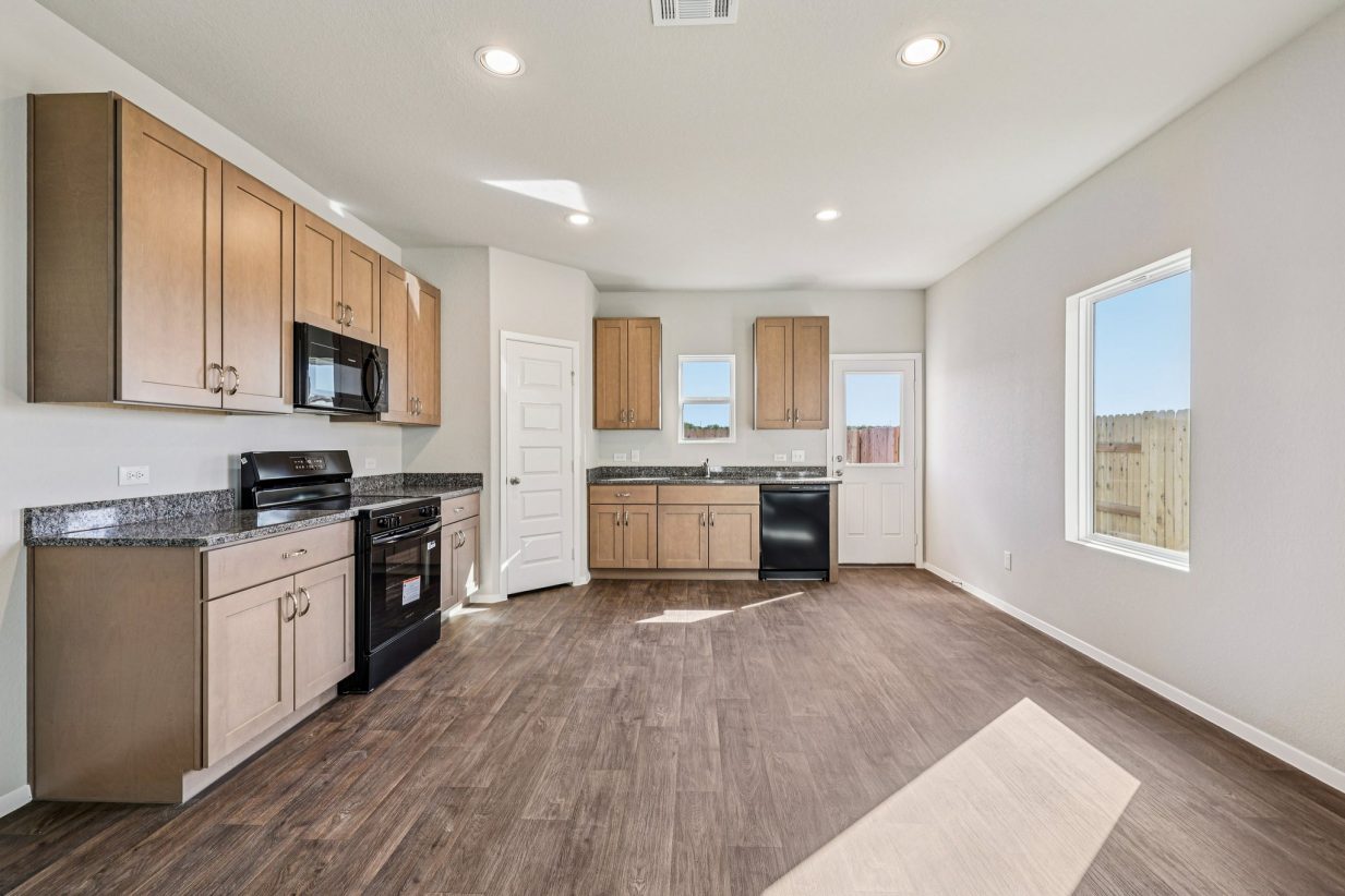 Image of a kitchen with brown cabinets, black appliance and a window above the sink