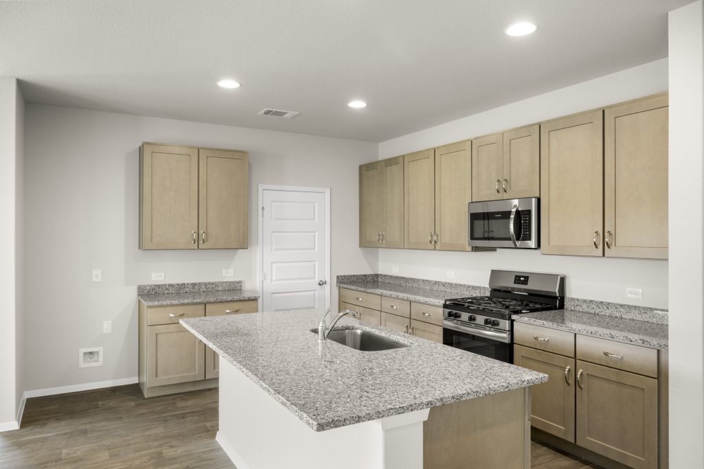 Image of home kitchen with light brown cabinets, center island, wood-look floors and white walls