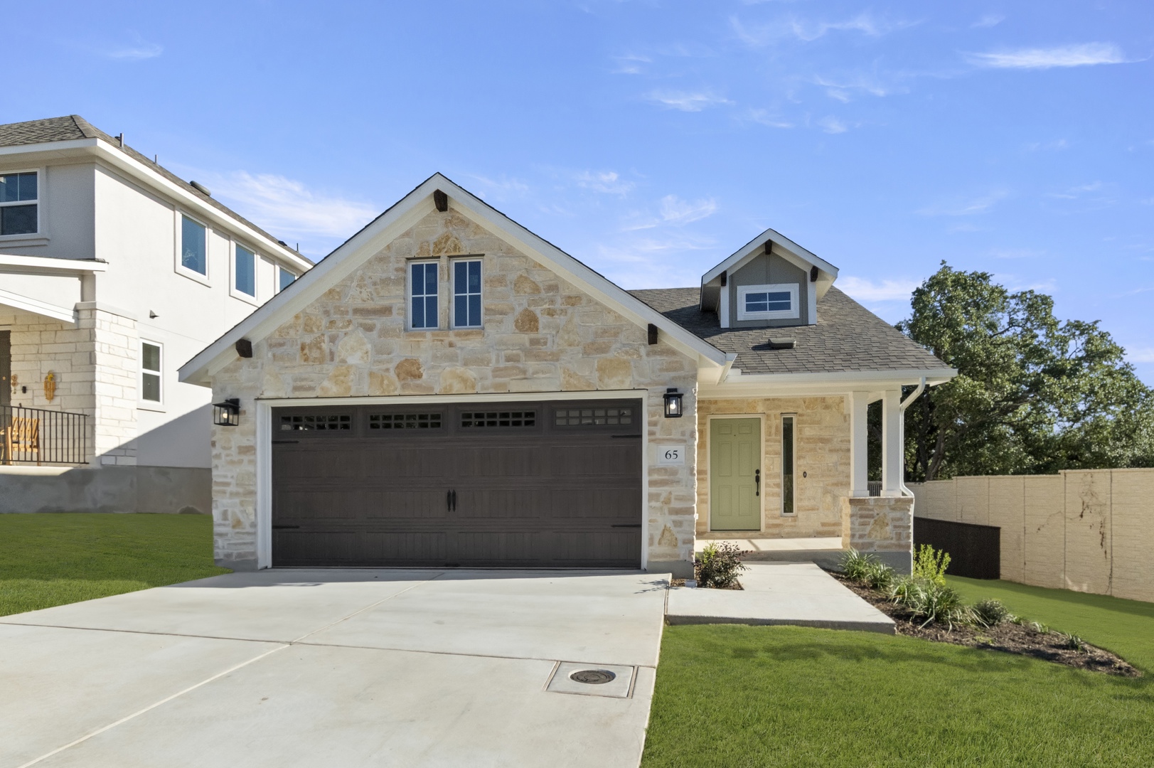 Front exterior image of brick house with brown garage door, driveway, and green landscape.