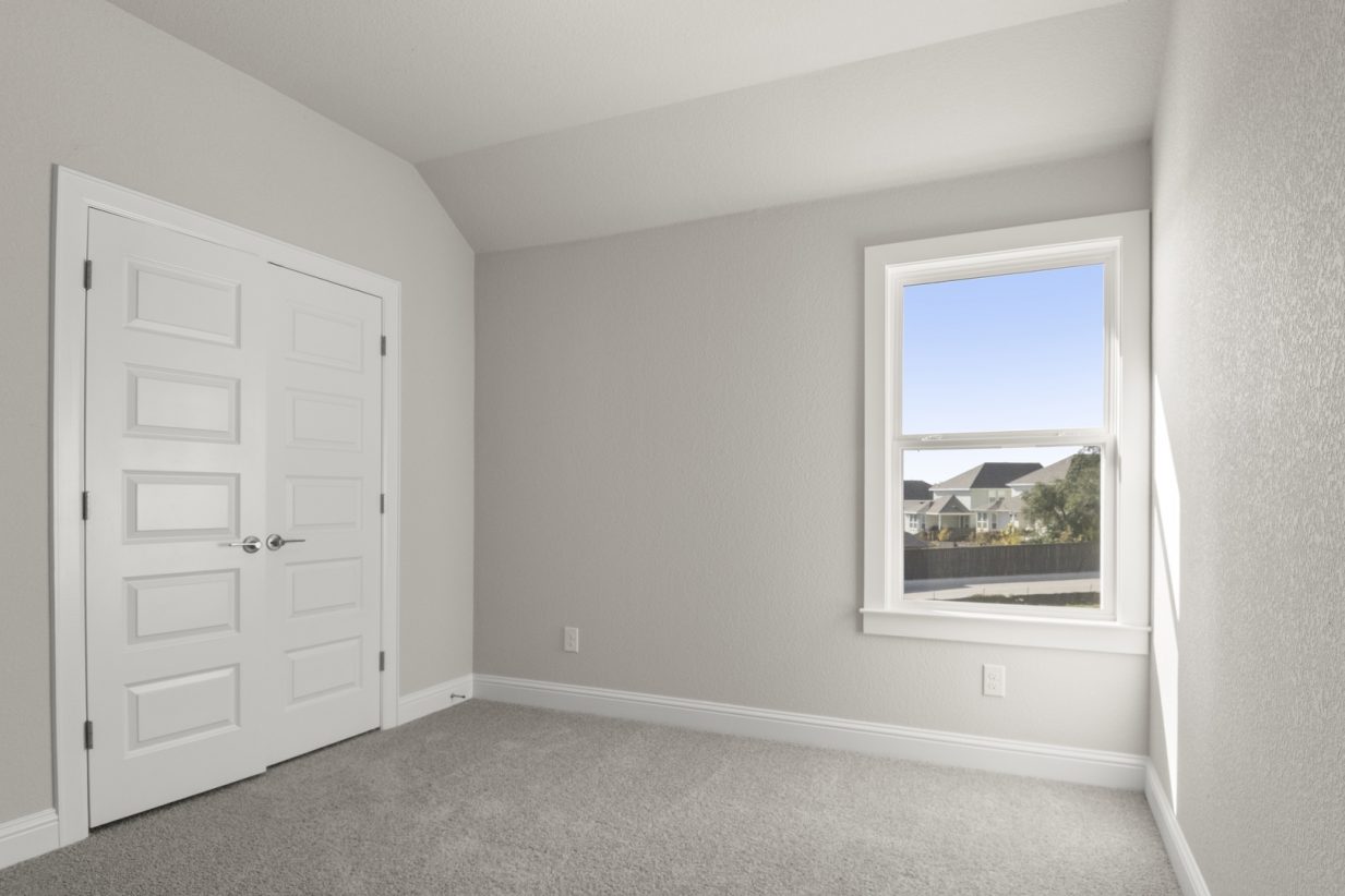 Image of a bedroom with light grey carpeting and painted walls with white doors leading to a closet