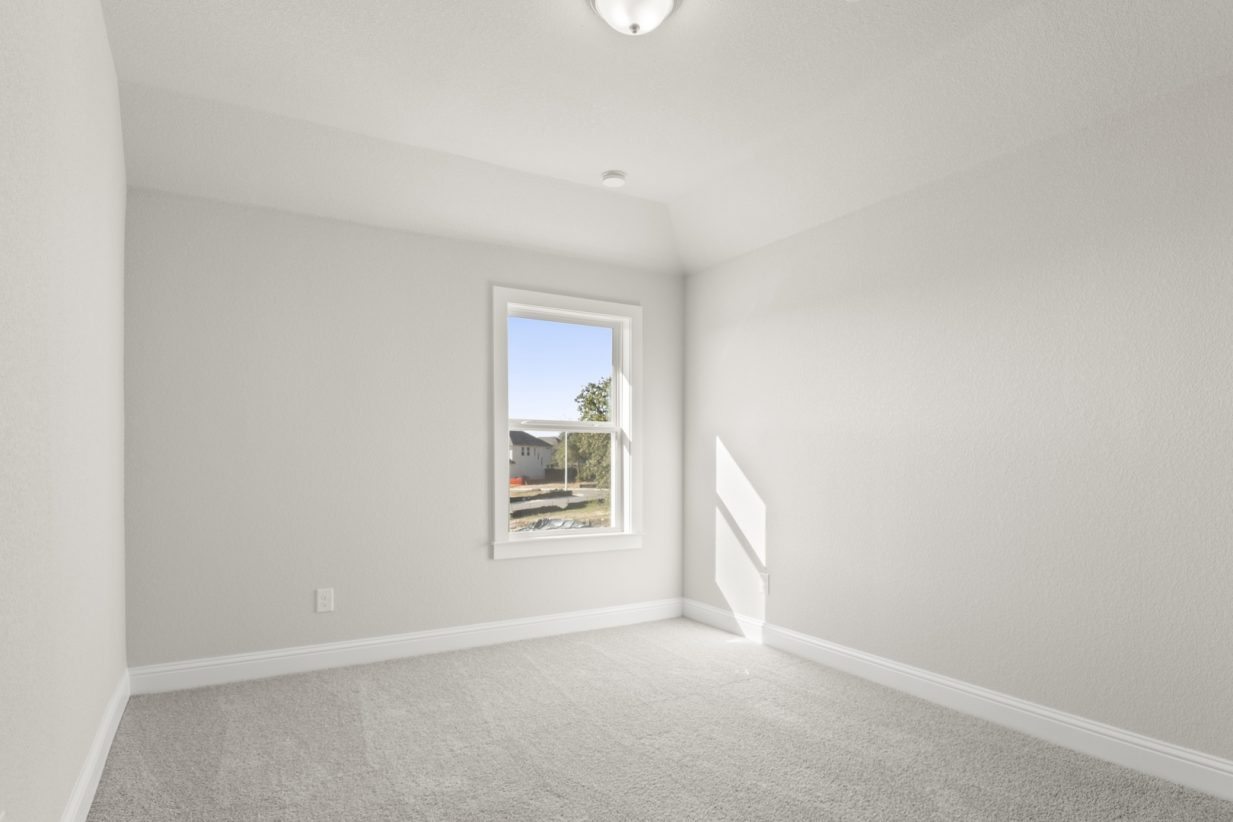 Image of a bedroom with light grey walls and carpeting with a window and white trim