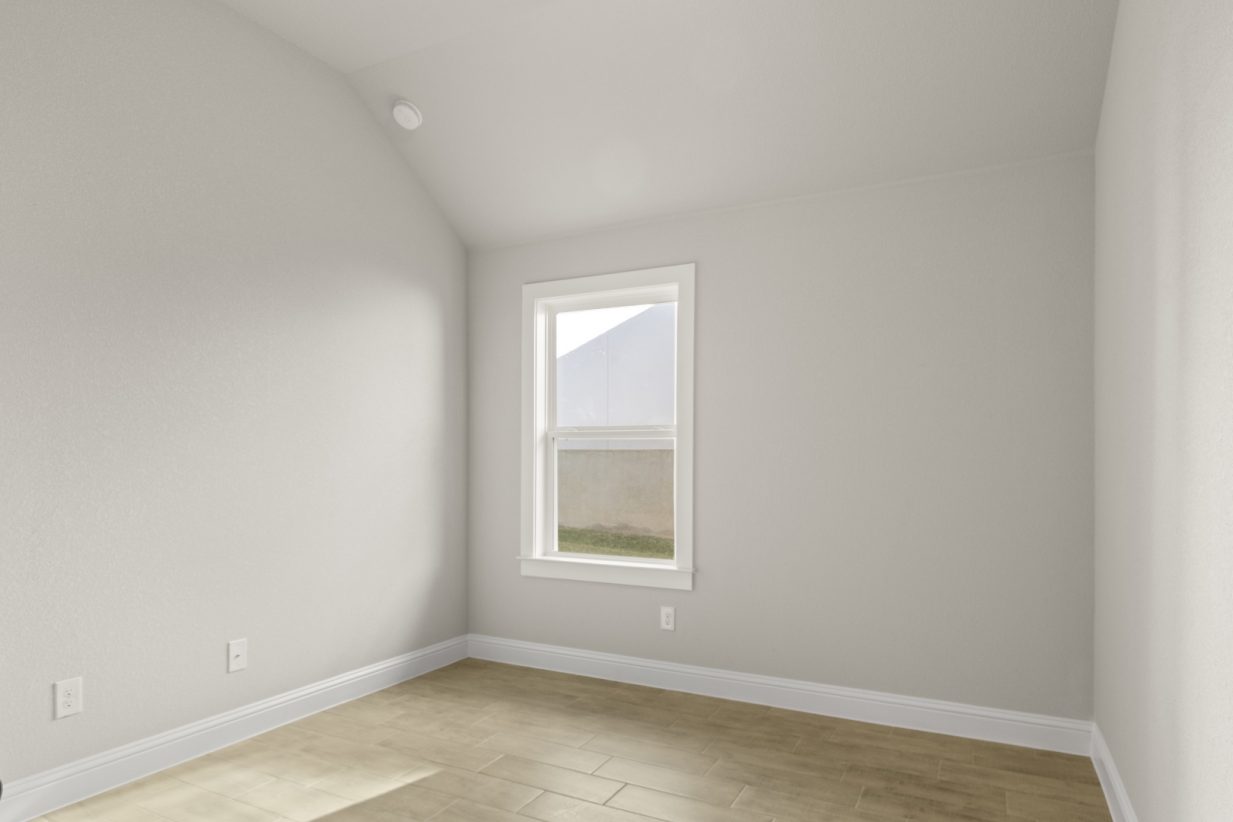 Image of a one story home bedroom with light wood-like flooring and light grey painted walls with a window in the corner