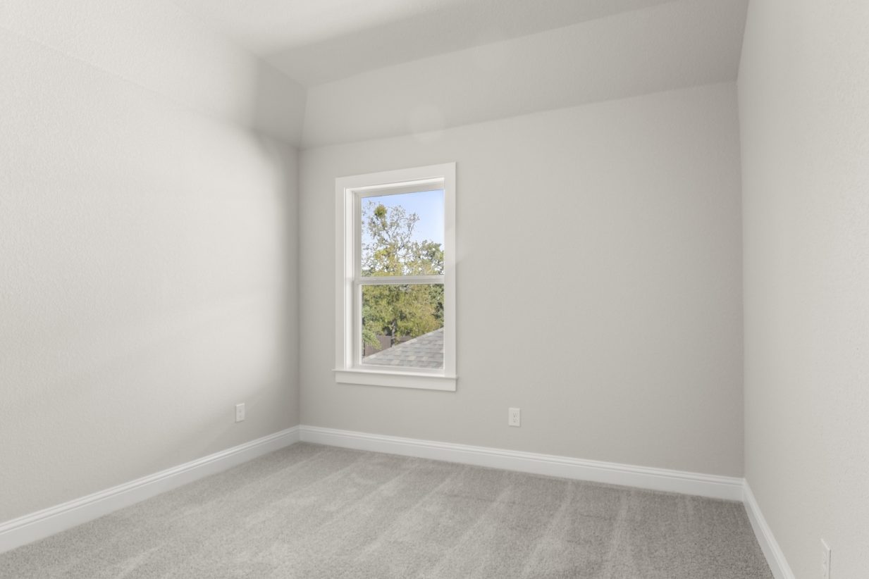 Image of a bedroom with light grey carpeting and painted walls with a window in the corner