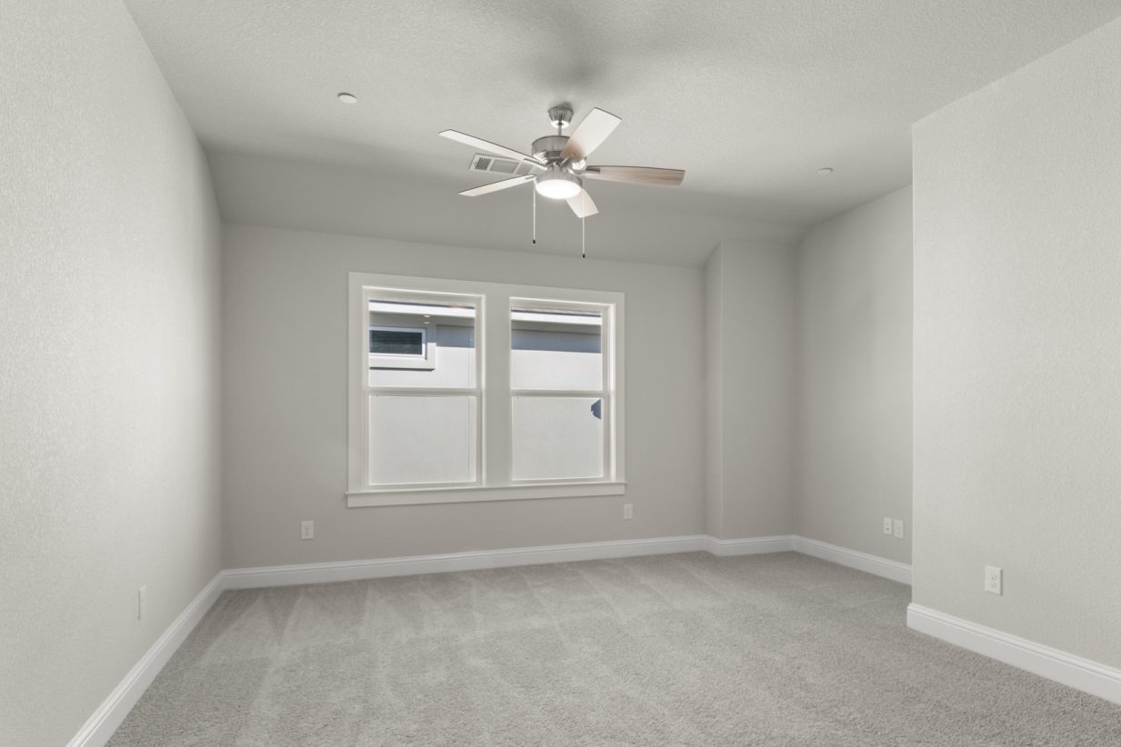 Image of a flex space with light grey carpeting and painted walls with two windows and a ceiling fan