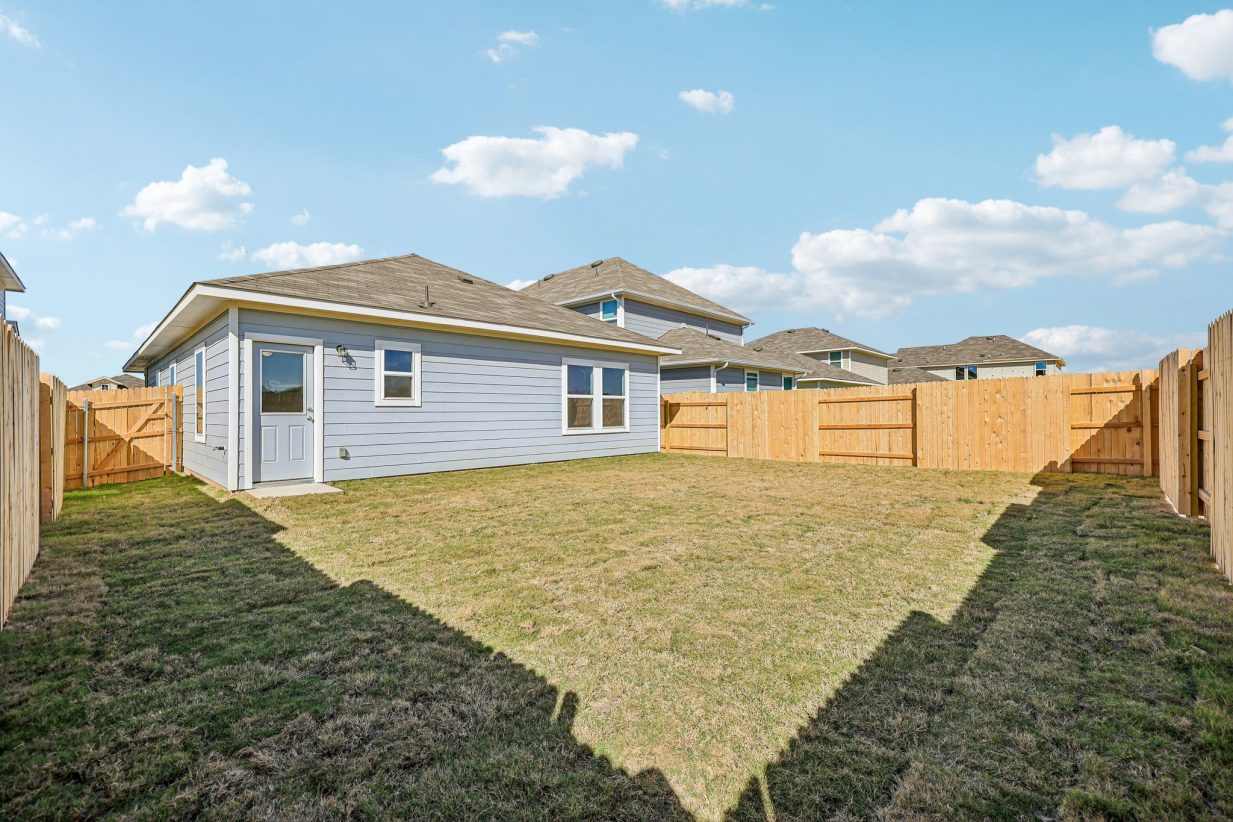 Image of a blue one story house with a wooden fence around the backyard