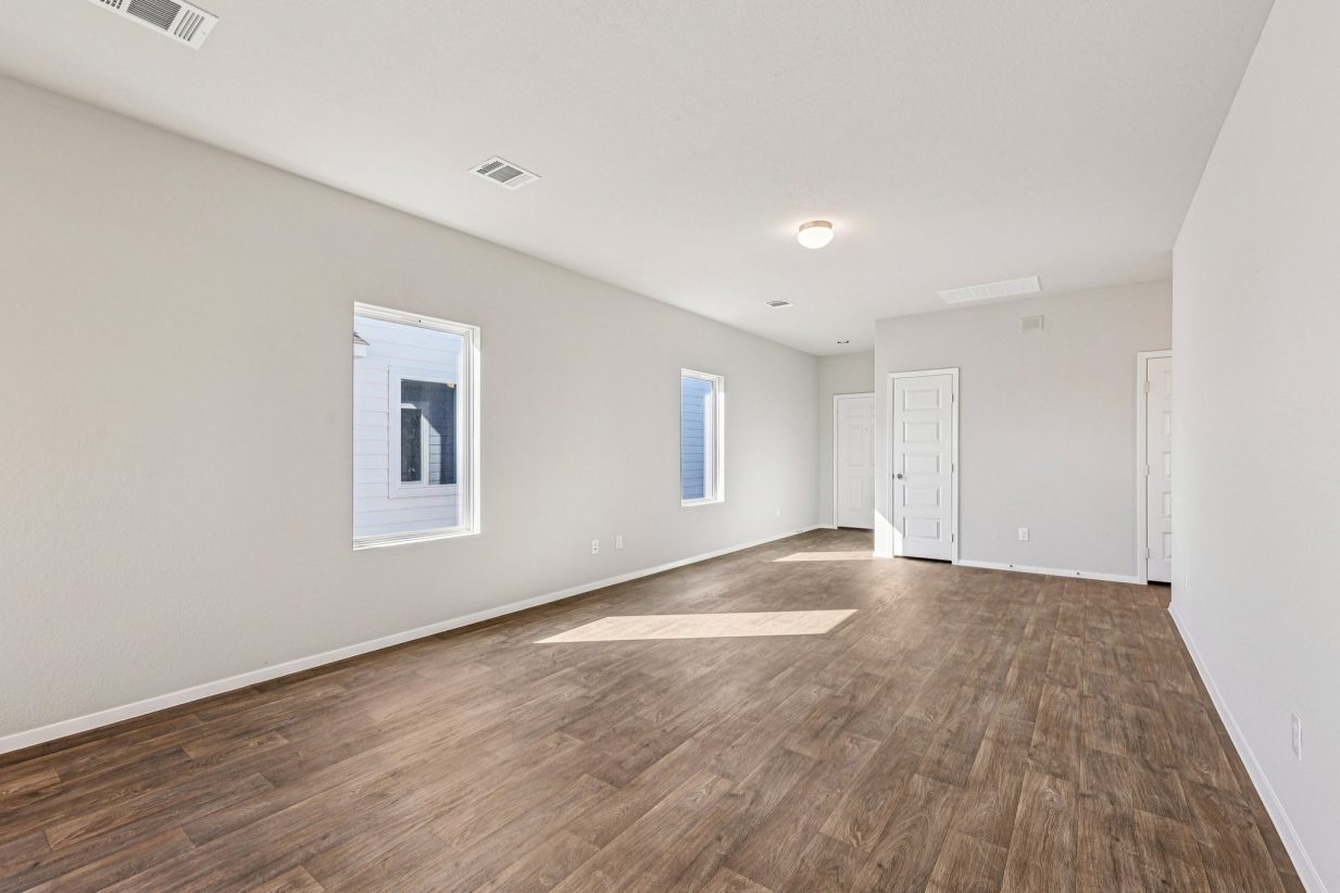Image of a living room with beige walls, vinyl flooring and windows