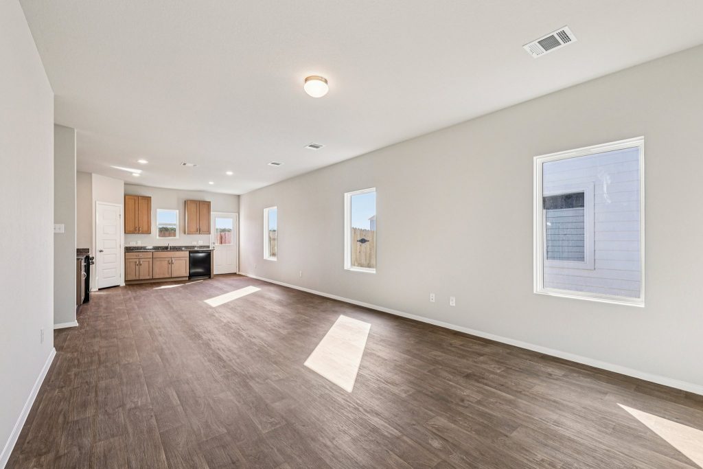 Image of a living room with beige walls, vinyl flooring and windows