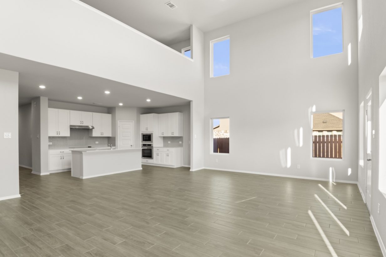 Image of a living room with high ceilings and dark wood-like flooring and and open layout kitchen