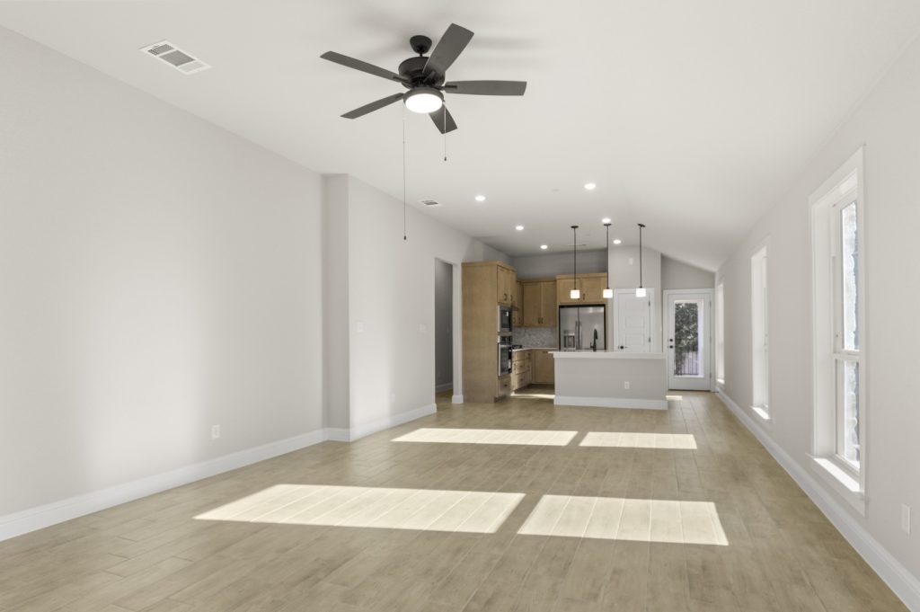 Image of a one story home living room with light wood-like flooring and light grey painted walls with two large windows and a ceiling fan