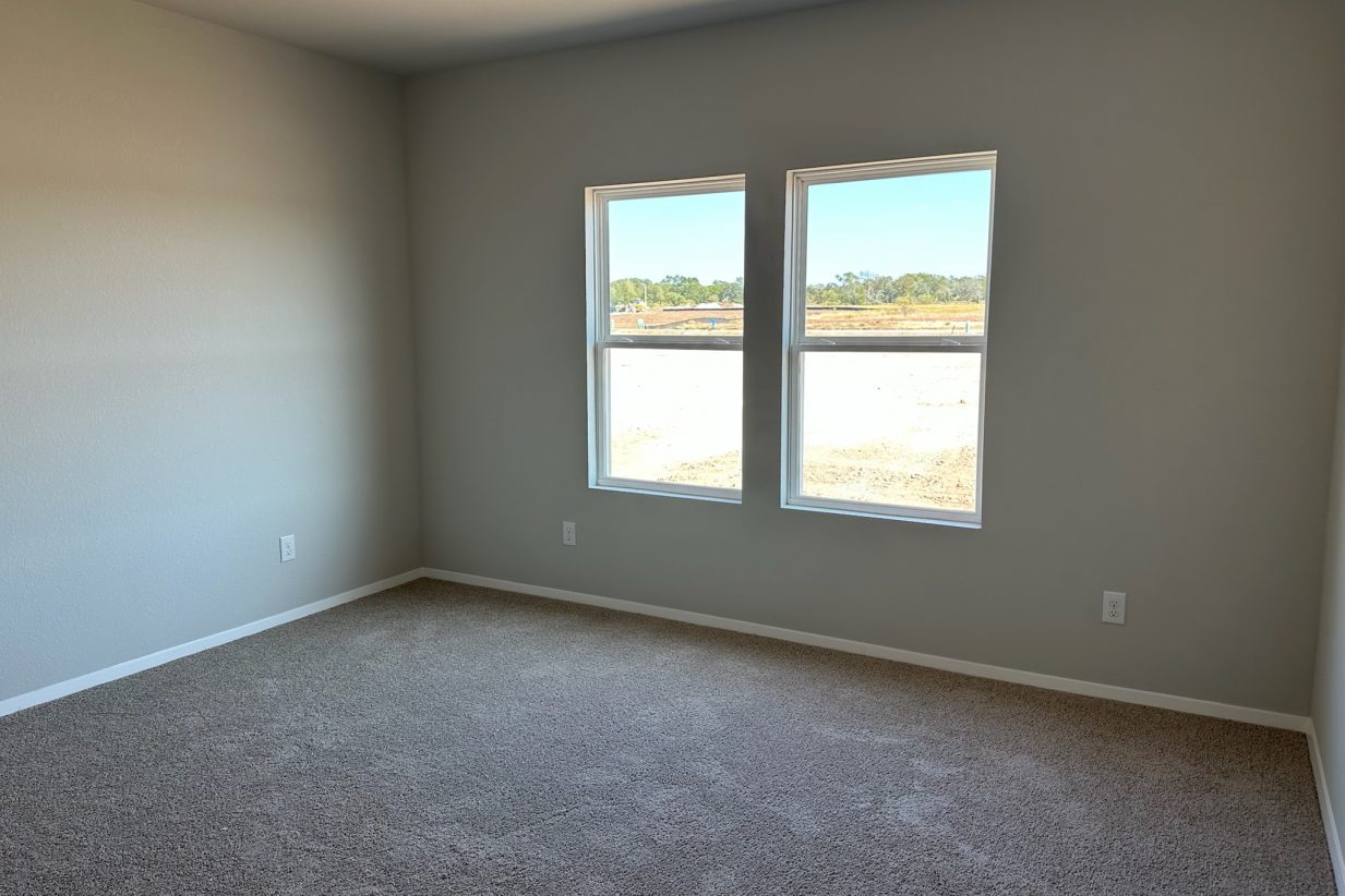 Photo of home primary bedroom with light carpet, white walls, and two windows