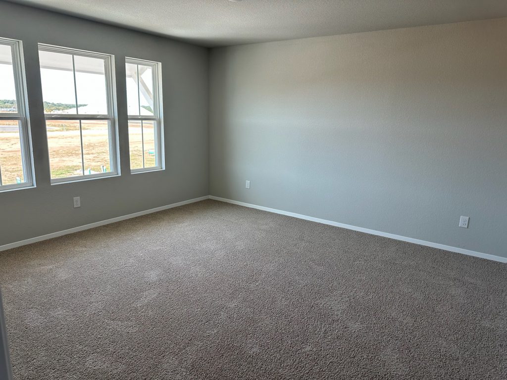 Image of home primary bedroom with light carpet, white walls, and windows