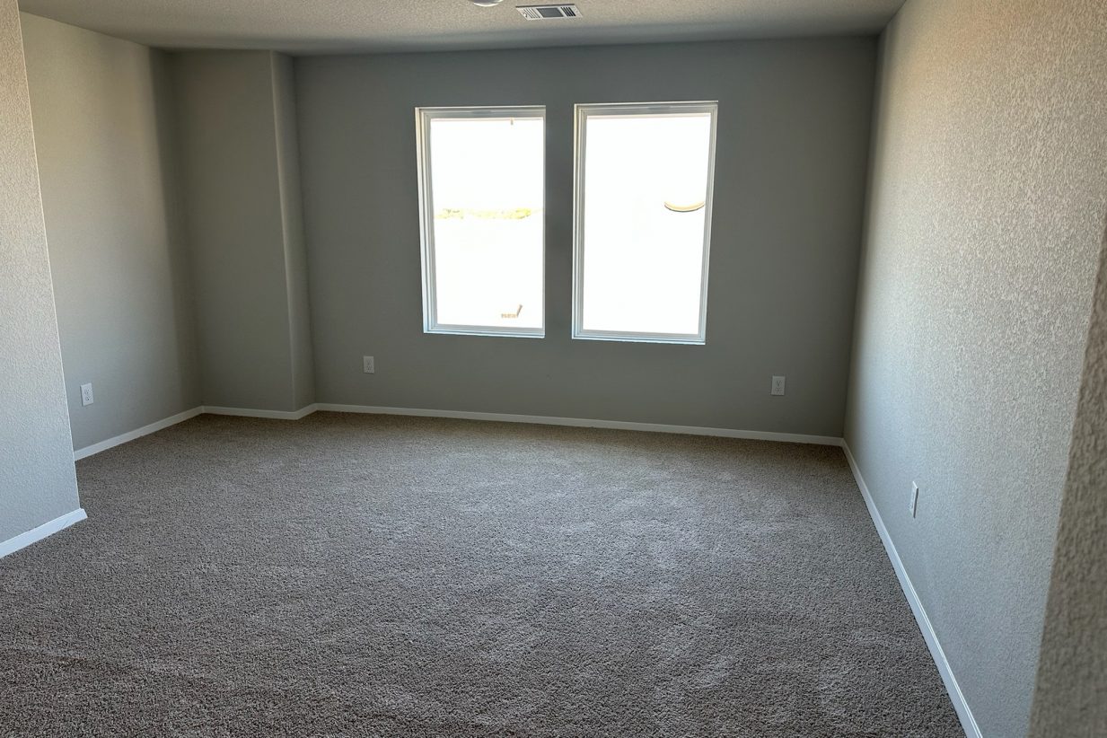 Image of home recreation room with light carpet, white walls, and windows